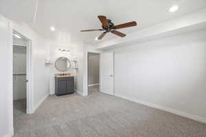 Bedroom #4 featuring light carpet, a spacious walk-in closet, hand-sink, recessed lighting, and ceiling fan