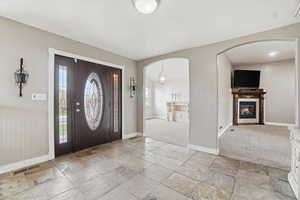 Spacious entryway foyer featuring arched walkways, stone tile floors
