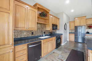 Kitchen with open shelves, black appliances, stone tile floors, dark countertops, and light wood finish cabinets