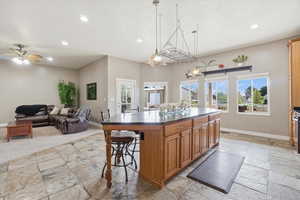 Kitchen featuring wood finish cabinetry, a breakfast bar, a center island, open floor plan, and ceiling fan