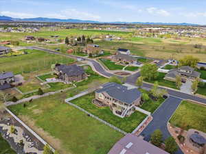 Aerial overview of property's fully fenced backyard and fully fenced horse pasture with surrounding upscale suburban area and a mountain backdrop