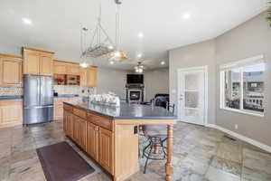 Kitchen featuring a breakfast bar area, dark countertops, freestanding refrigerator, a ceiling fan, and a center island
