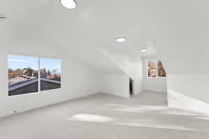 Bonus room featuring vaulted ceiling and light colored carpet