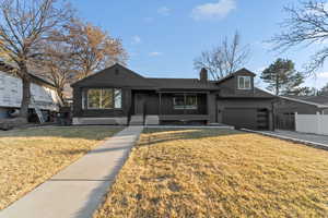 View of front of home featuring a chimney and concrete driveway