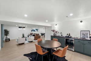 Dining area with beverage cooler, light wood finished floors, wet bar, and recessed lighting