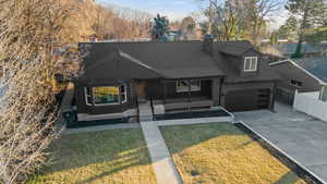 View of front of property featuring driveway, a shingled roof, covered porch, and a chimney
