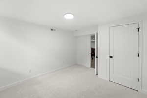 Unfurnished bedroom with light carpet and baseboards