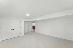 Finished basement featuring light colored carpet and a textured ceiling
