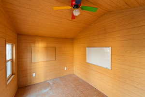 Spare room with a vaulted wooden ceiling, parquet floors, a ceiling fan, and wood walls