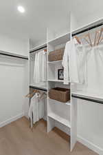 Walk in closet with light wood-style floors