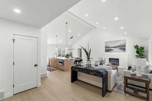 Living area with light wood finished floors, a glass covered fireplace, and recessed lighting