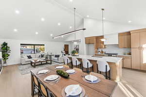Dining space with light wood finished floors, lofted ceiling, and recessed lighting