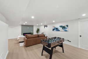 Recreation room with light wood-style floors and recessed lighting