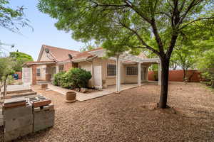 Rear view of property featuring a tile roof, stucco siding, and a fenced backyard