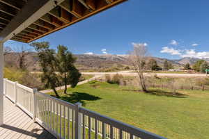 Wooden deck with a fenced backyard, a mountain view, and a view of rural / pastoral area