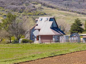 View of front of house featuring a storage unit, a metal roof, and a view of countryside