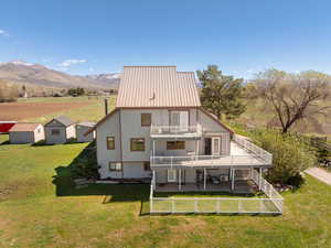 Rear view of property with a view of countryside, a balcony, a fenced backyard, a mountain view, and a metal roof