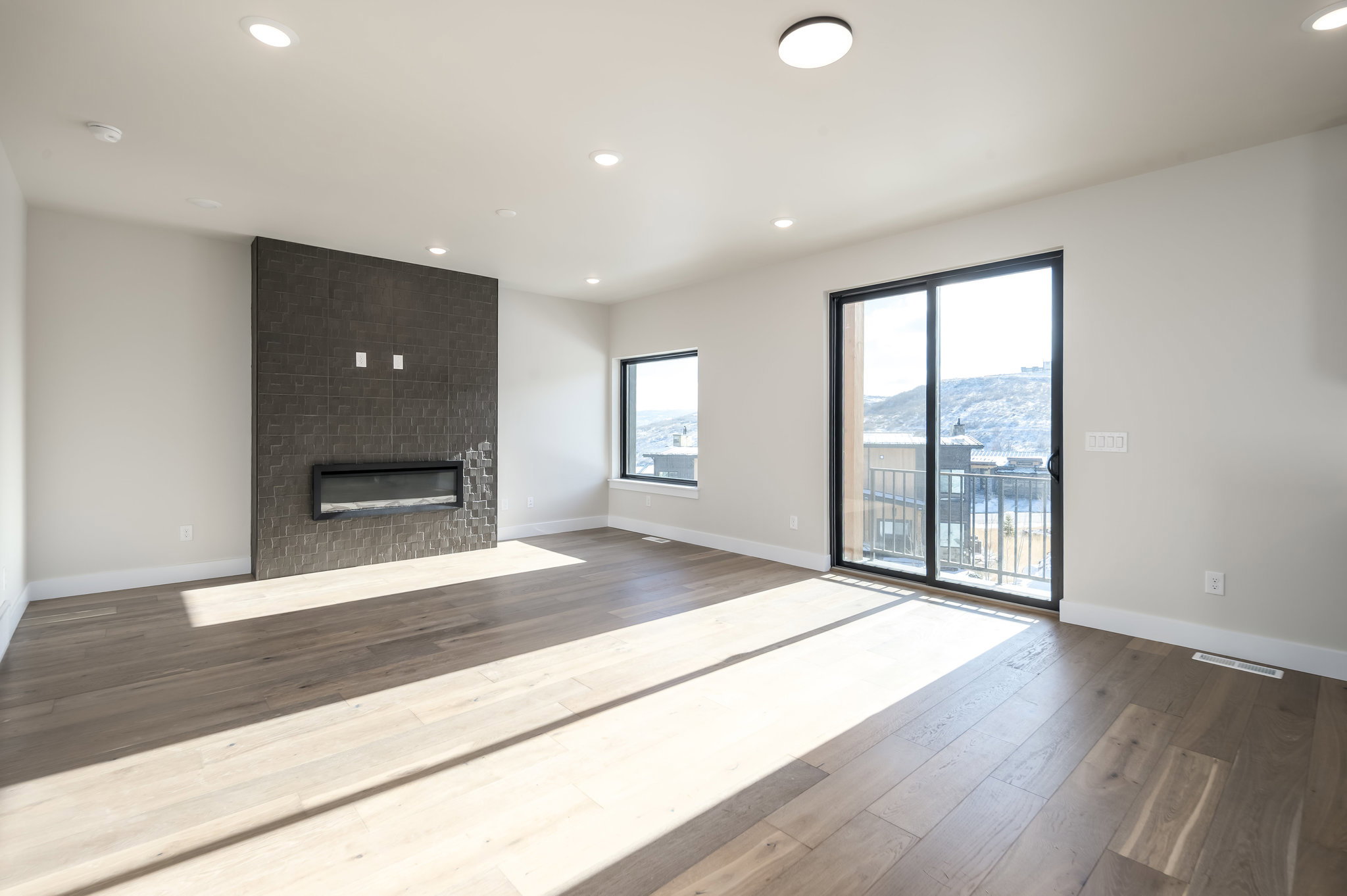 Unfurnished living room featuring a large fireplace, dark wood-style flooring, recessed lighting, and a mountain view