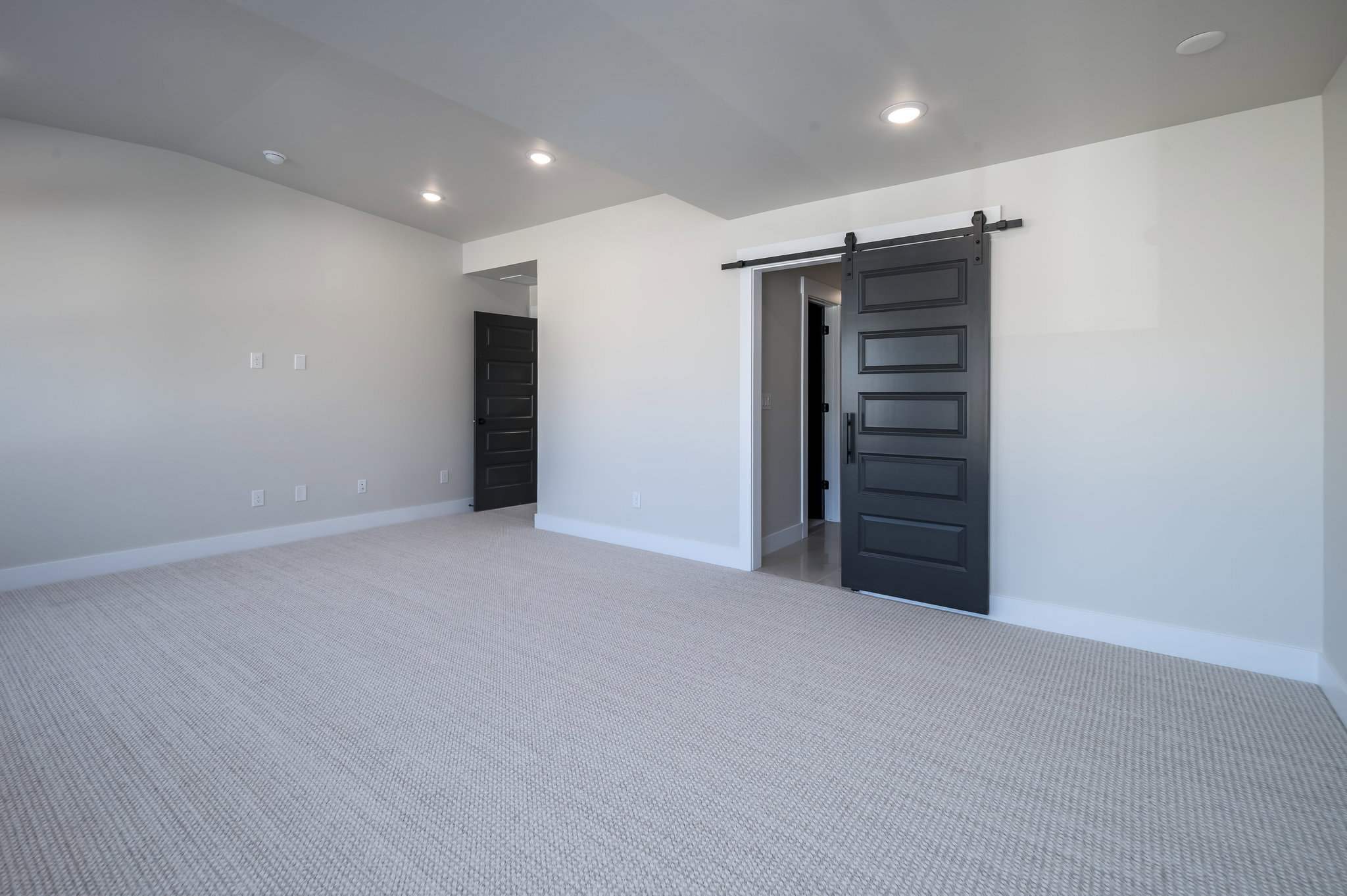 Empty room featuring a barn door, carpet, recessed lighting, and lofted ceiling