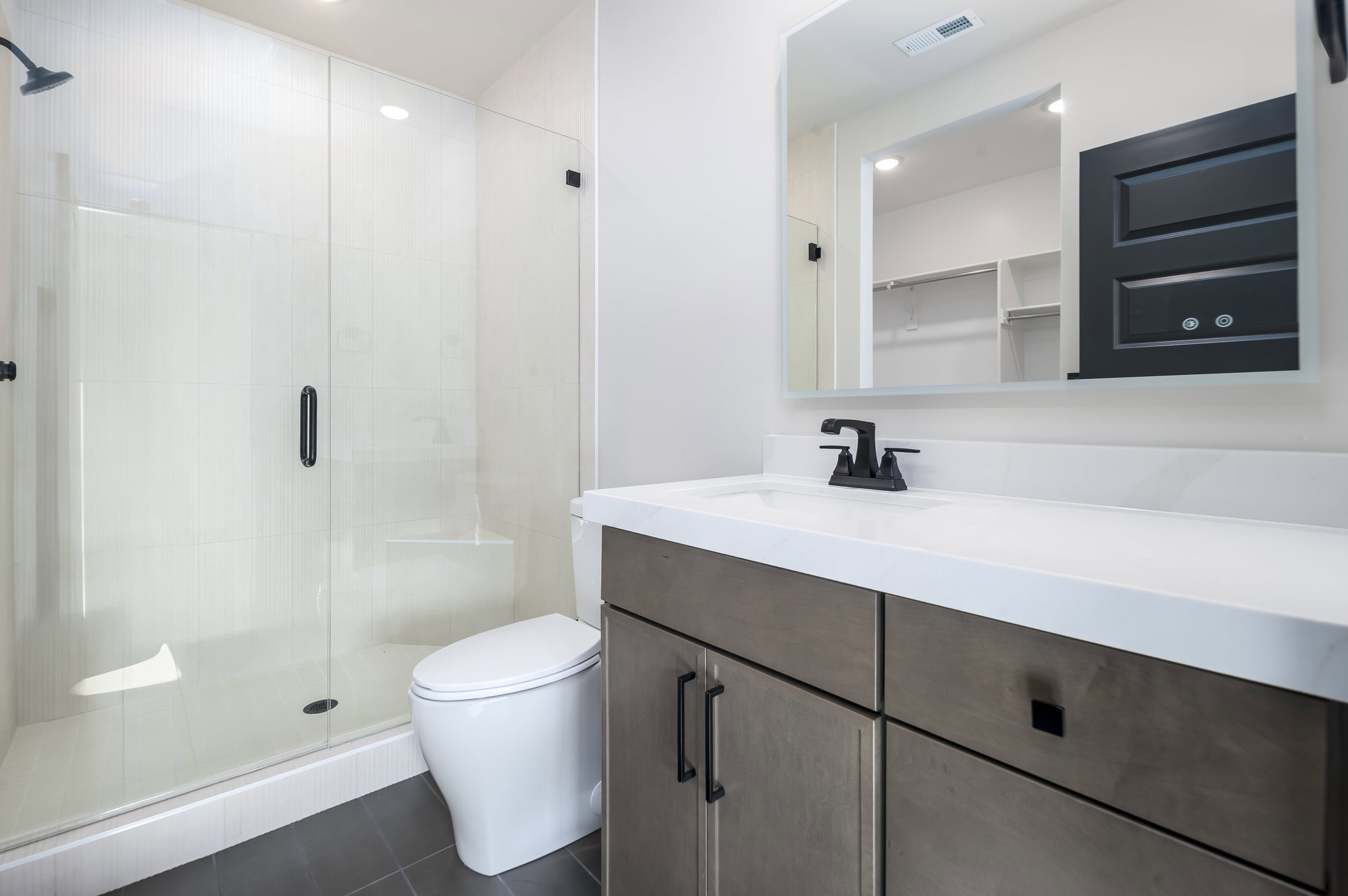 Full bathroom featuring vanity, a shower stall, a spacious closet, dark tile patterned floors, and recessed lighting