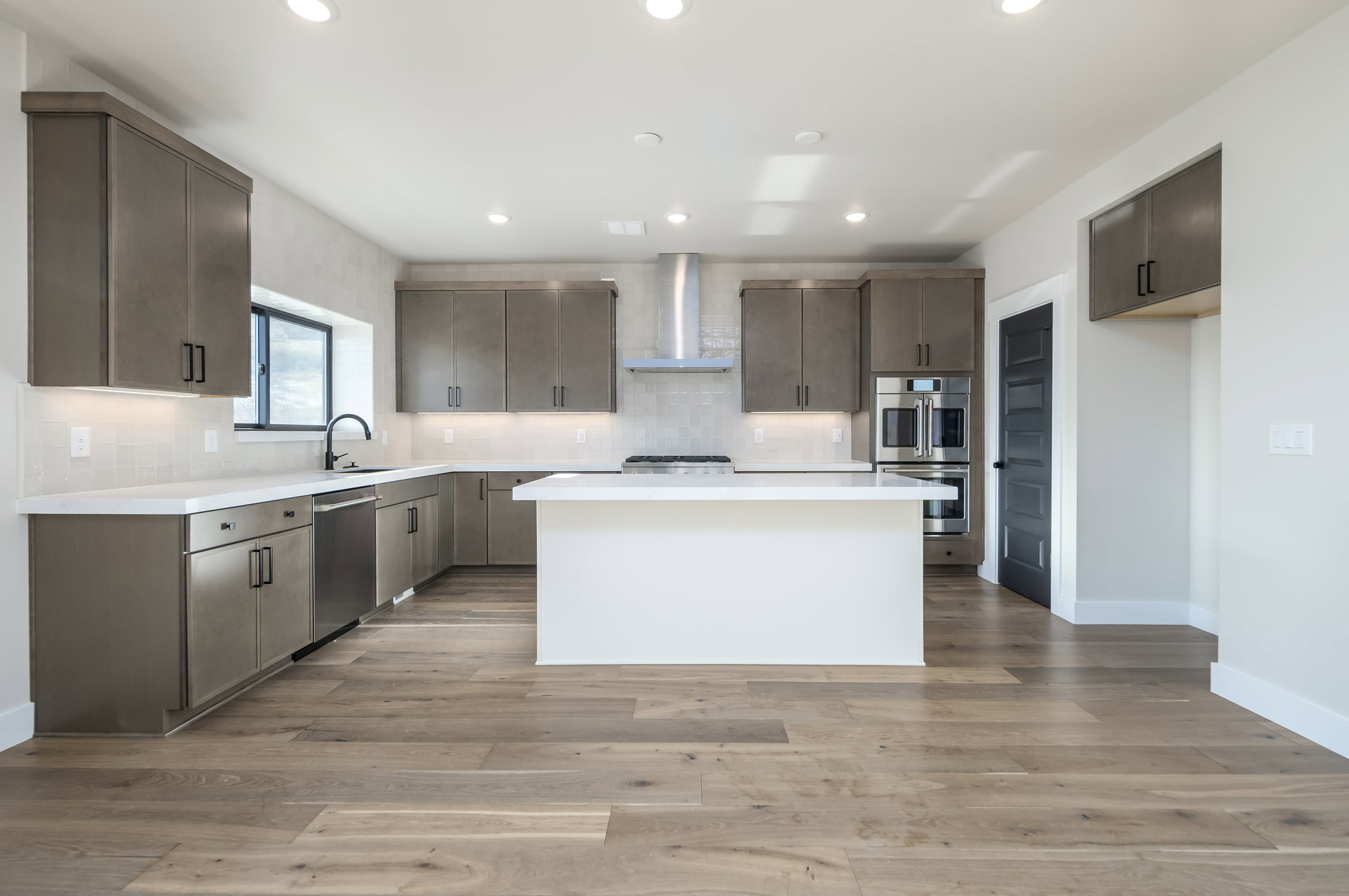 Kitchen with backsplash, dark wood finish cabinets, light wood-type flooring, and recessed lighting