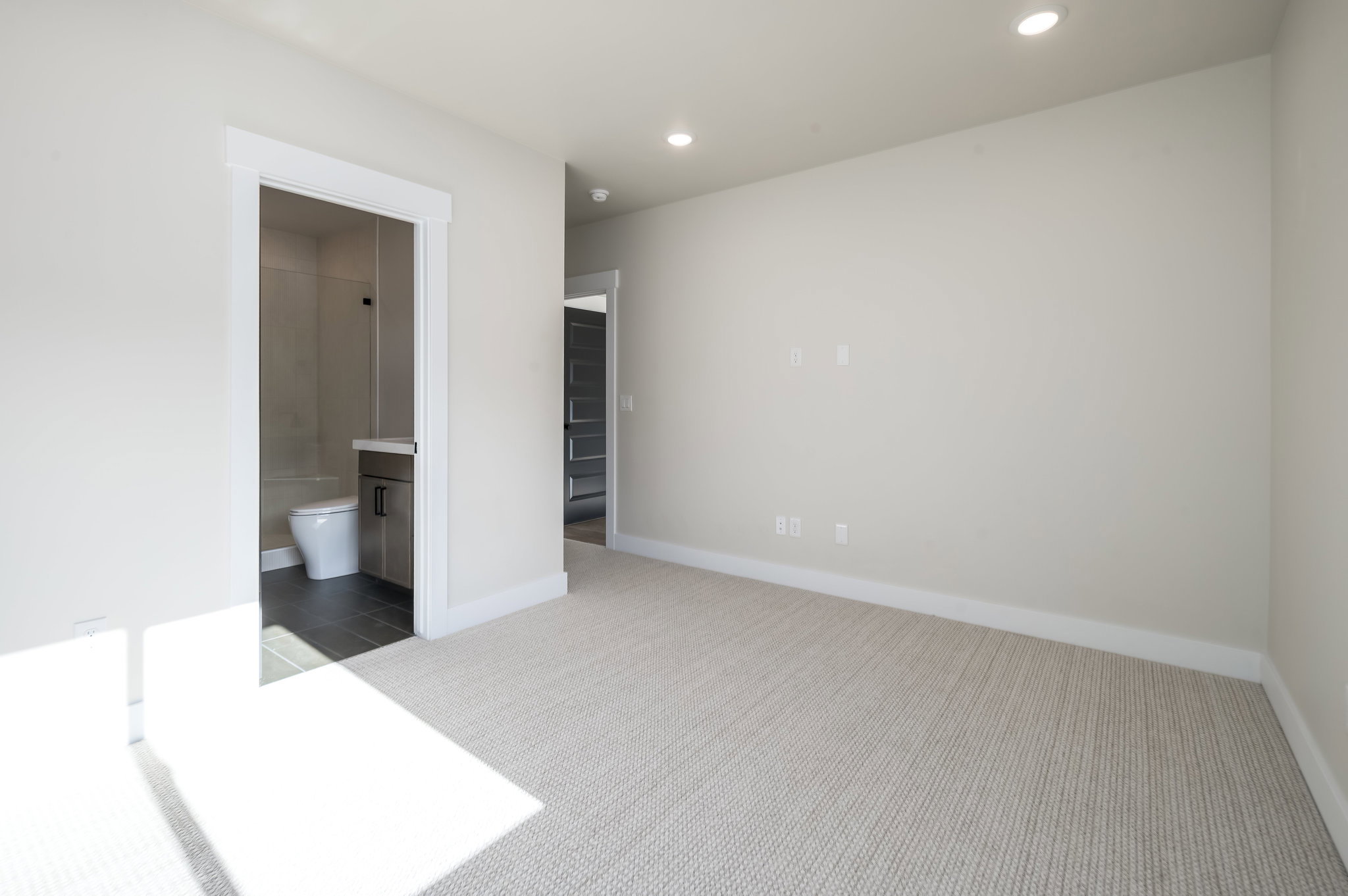 Unfurnished bedroom featuring light carpet, recessed lighting, and ensuite bath