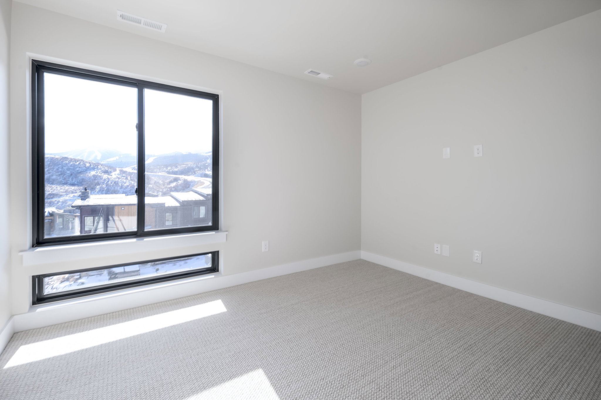 Empty room with light colored carpet and a mountain view