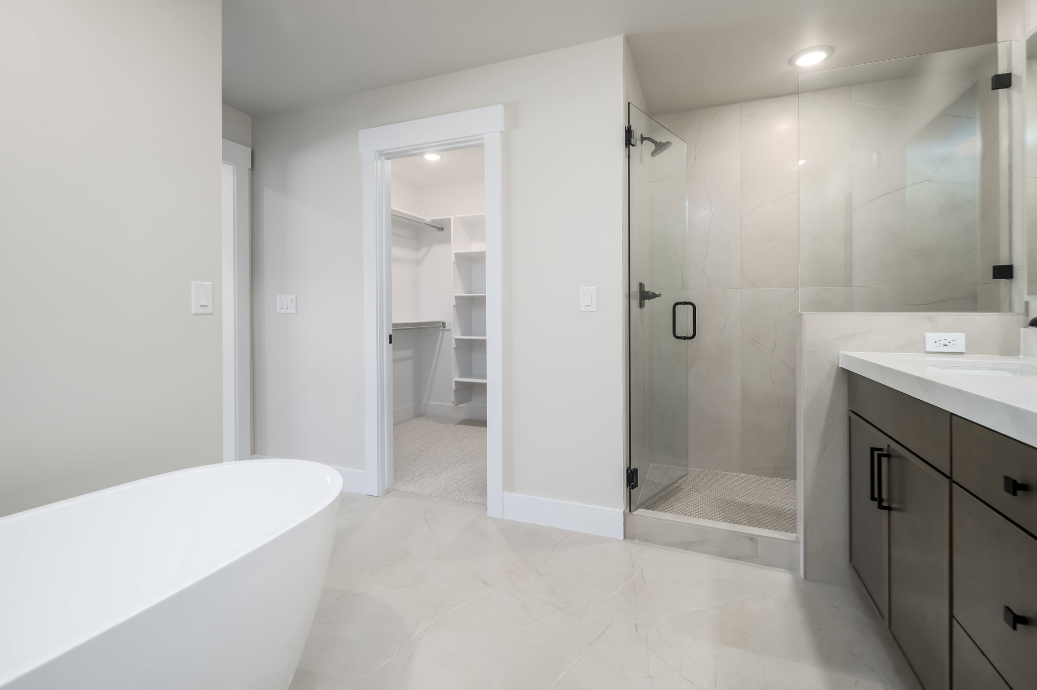 Full bathroom with a walk in closet, a shower stall, a freestanding bath, vanity, and recessed lighting