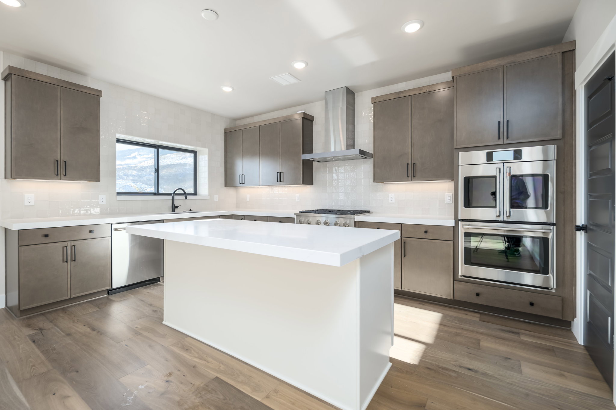 Kitchen featuring stainless steel appliances, decorative backsplash, a kitchen island, light wood-style flooring, and recessed lighting