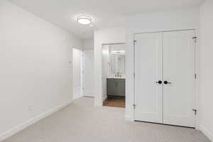 Unfurnished bedroom featuring light colored carpet, a closet, and connected bathroom