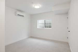Unfurnished room with light colored carpet and a wall mounted mini split