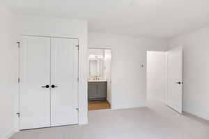 Unfurnished bedroom with light carpet, a closet, and ensuite bathroom