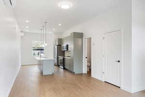Kitchen with gray cabinets, light countertops, a center island with sink, and light wood-style flooring