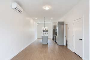 Kitchen with a center island with sink, light countertops, gray cabinetry, light wood finished floors, and stainless steel electric range oven