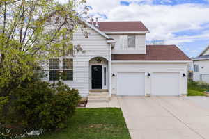 Traditional-style home featuring driveway, roof with shingles, and a front yard