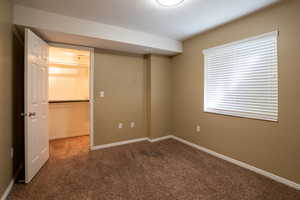 Unfurnished bedroom with a walk in closet and dark colored carpet