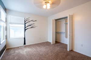 Unfurnished bedroom with carpet, a closet, and a ceiling fan