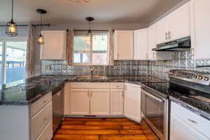Kitchen featuring stainless steel appliances, tile countertops, white cabinets, and a peninsula