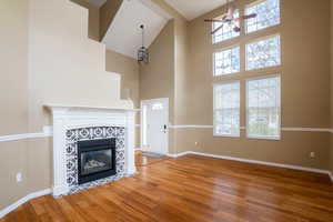 Unfurnished living room featuring a tiled fireplace, ceiling fan, light wood finished floors, and vaulted ceiling