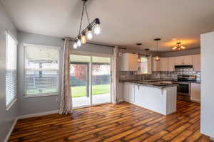 Kitchen with a breakfast bar area, electric range, decorative backsplash, dark stone countertops, and white cabinets