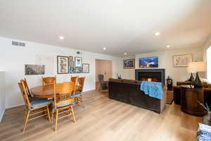 Dining room featuring light wood finished floors, a lit fireplace, and recessed lighting