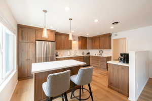 Kitchen featuring wood finish cabinets, stainless steel appliances, tasteful backsplash, and light wood finished floors