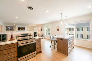 Kitchen featuring stainless steel appliances, wood finish cabinetry, light wood finished floors, a kitchen island, and open floor plan
