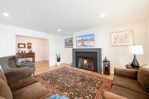 Living area featuring light wood-style floors, a glass covered fireplace, and recessed lighting