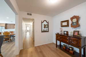Hallway with light wood finished floors and recessed lighting