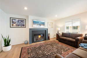 Living room with light wood-style floors, a fireplace with flush hearth, and recessed lighting