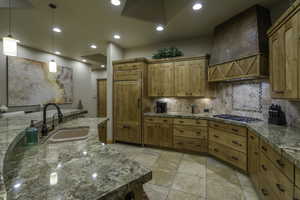 Kitchen with pendant lighting, tasteful backsplash, wood finish cabinets, paneled fridge, and stainless steel gas cooktop