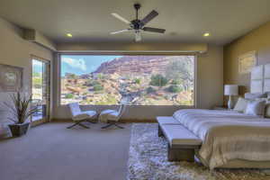 Carpeted bedroom featuring access to outside, a ceiling fan, multiple windows, and a mountain view