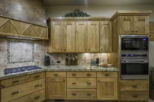Kitchen featuring stainless steel appliances, range hood, tile countertops, and backsplash