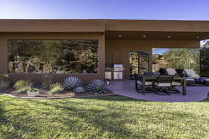 Rear view of property featuring a patio area, stucco siding, and a lawn